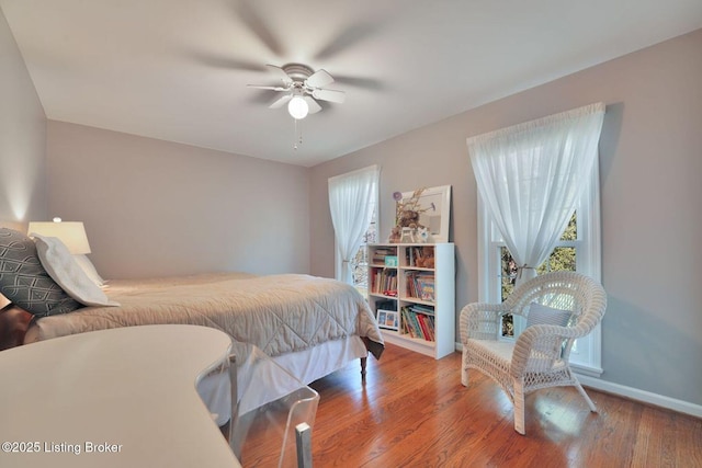 bedroom with multiple windows, ceiling fan, baseboards, and wood finished floors