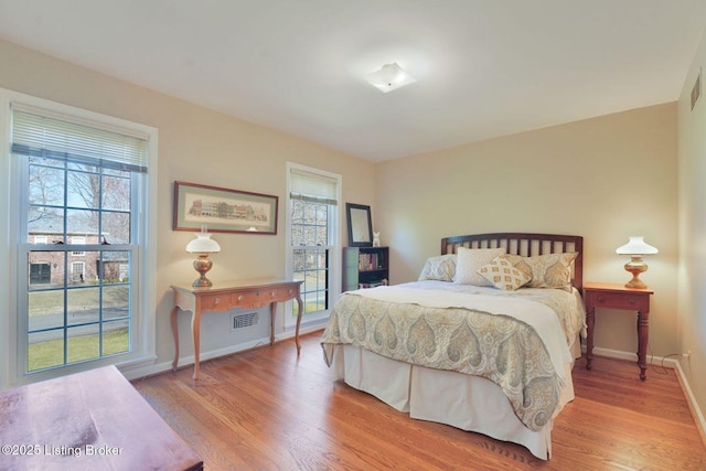 bedroom featuring wood finished floors, visible vents, and baseboards