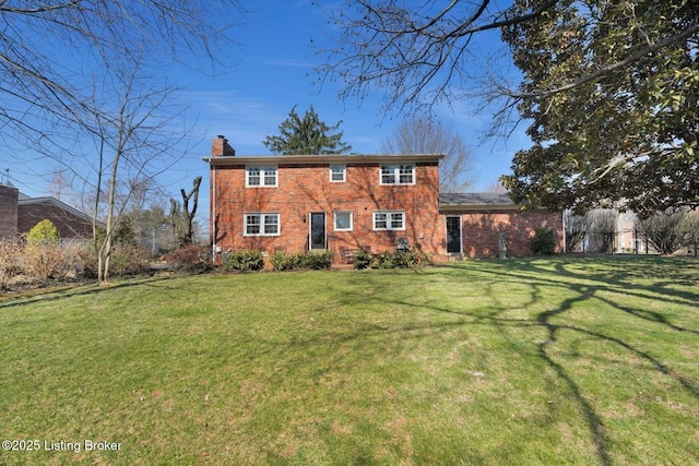 colonial home featuring a front lawn, brick siding, and a chimney