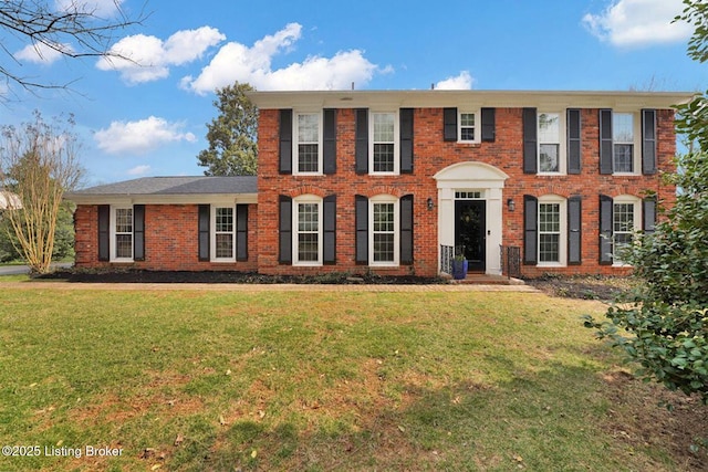 colonial home featuring a front lawn and brick siding