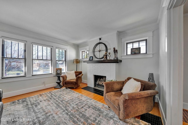 living area featuring crown molding, a brick fireplace, wood finished floors, and baseboards