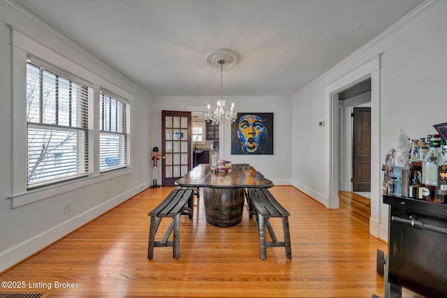 dining room featuring crown molding, baseboards, light wood finished floors, and a chandelier