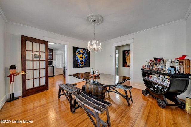 dining room featuring an inviting chandelier, baseboards, light wood-style floors, and ornamental molding