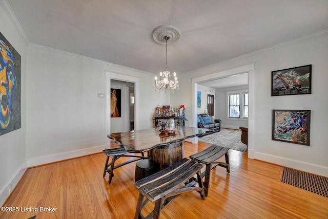 dining space with visible vents, light wood-style floors, crown molding, baseboards, and a chandelier