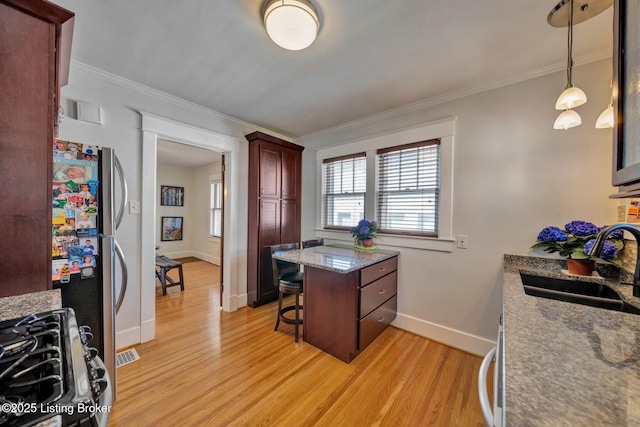 kitchen featuring range with gas stovetop, ornamental molding, a breakfast bar, and a sink