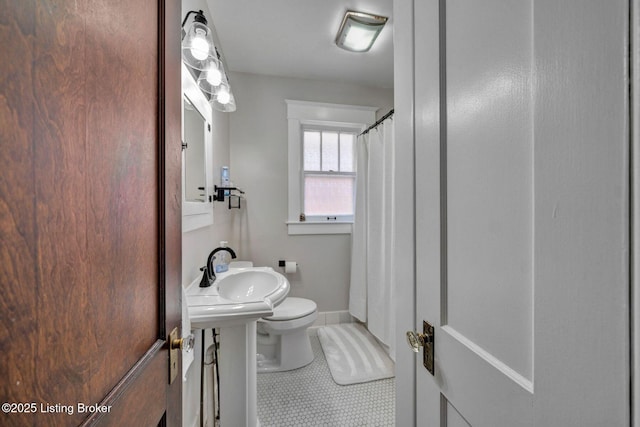 bathroom featuring a sink, baseboards, toilet, and tile patterned flooring