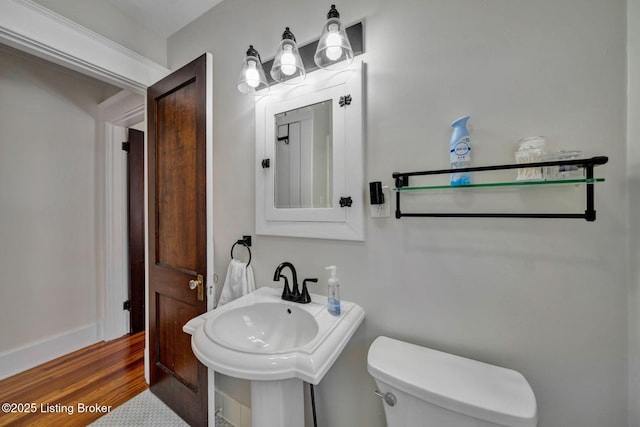 half bathroom with toilet and wood finished floors