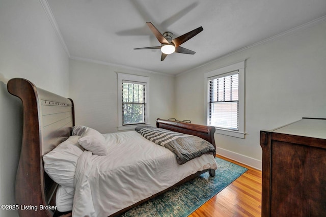 bedroom with multiple windows, wood finished floors, baseboards, and ornamental molding