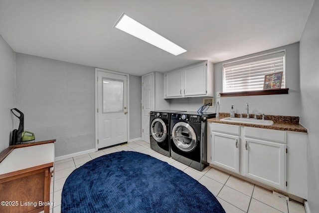 clothes washing area with light tile patterned floors, baseboards, cabinet space, a sink, and washer and clothes dryer