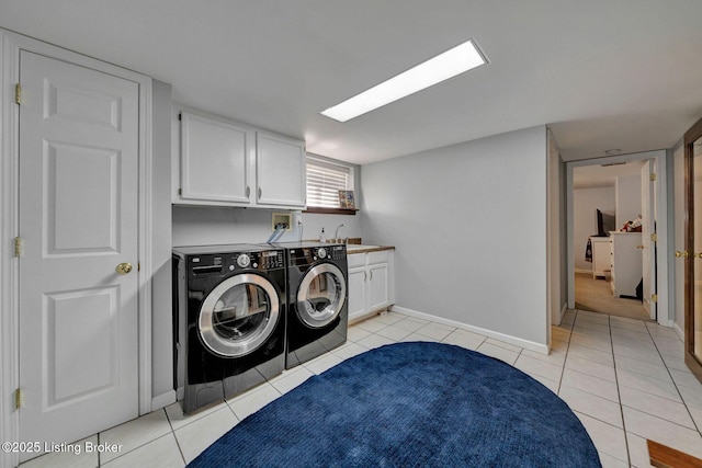 laundry area with baseboards, washer and clothes dryer, light tile patterned floors, cabinet space, and a sink