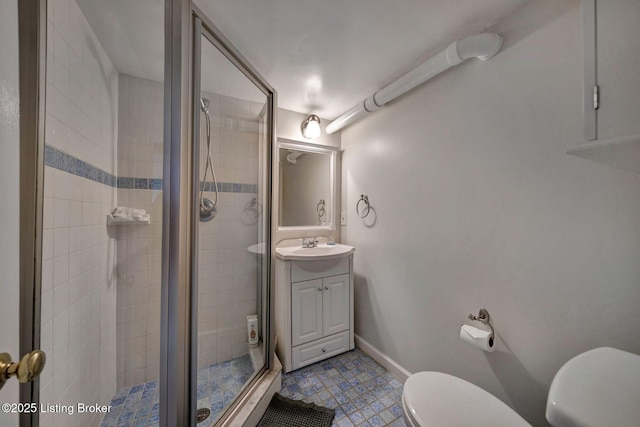 bathroom with a shower stall, toilet, vanity, and baseboards