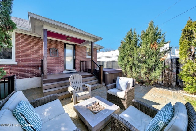 view of patio / terrace featuring an outdoor living space with a fire pit, fence, and a hot tub