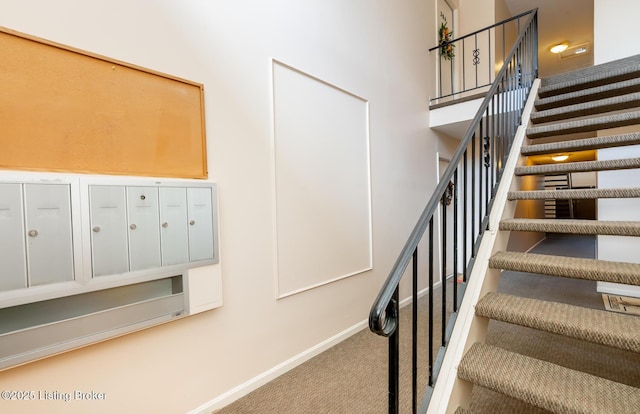 staircase with mail area, a high ceiling, baseboards, and carpet floors