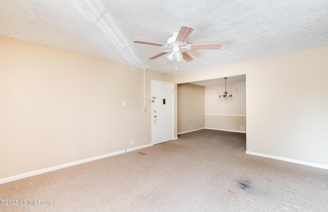 carpeted spare room featuring ceiling fan with notable chandelier, a textured ceiling, and baseboards