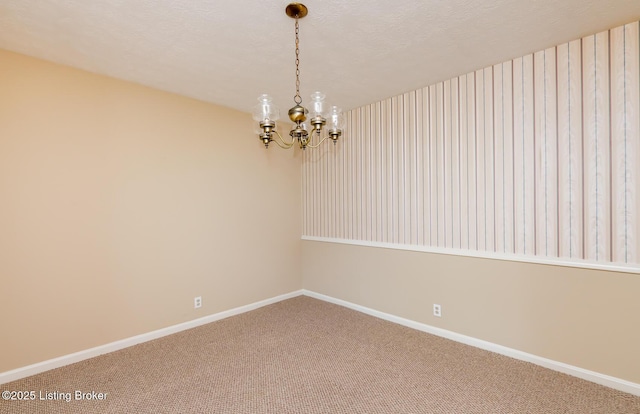 unfurnished room featuring a chandelier, carpet flooring, a textured ceiling, and baseboards