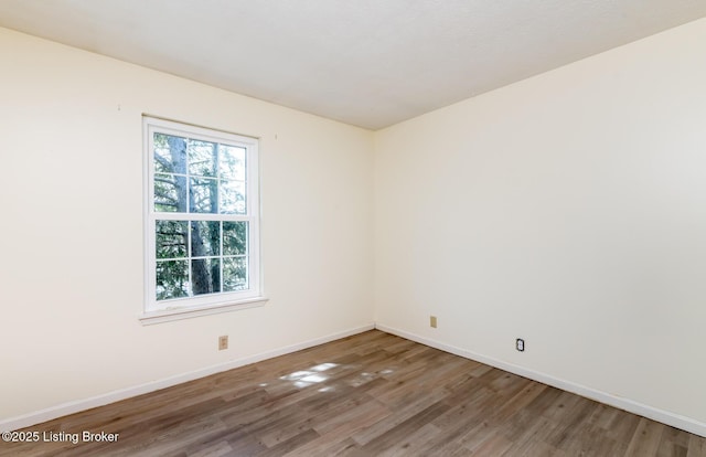 empty room featuring wood finished floors and baseboards