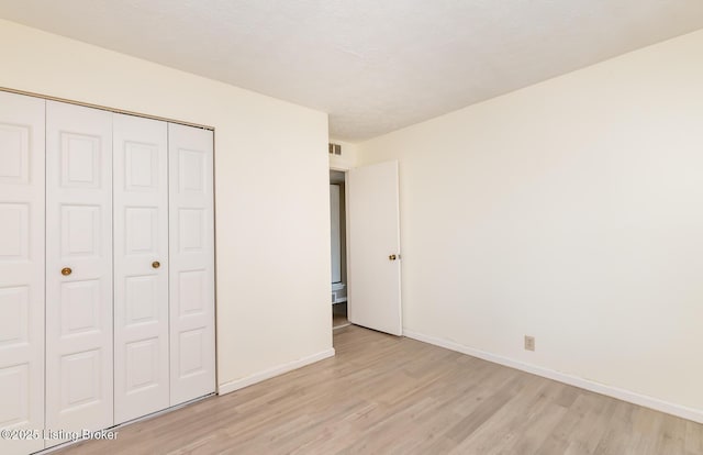 unfurnished bedroom featuring a closet, visible vents, light wood-type flooring, and baseboards