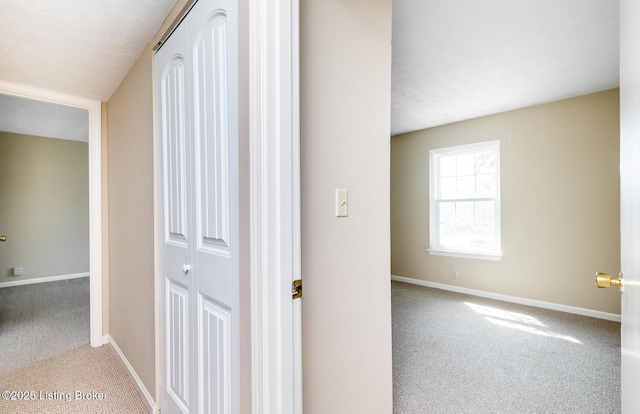 corridor with baseboards and carpet flooring