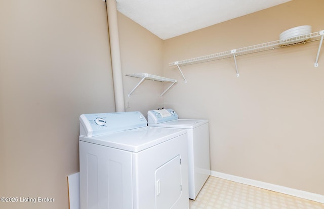 clothes washing area featuring baseboards, light floors, laundry area, and washing machine and clothes dryer