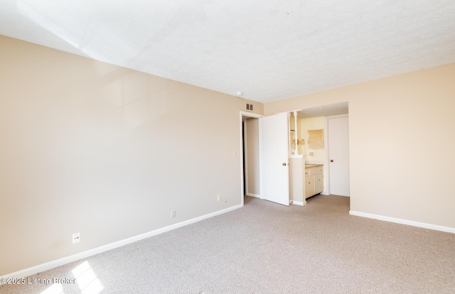 unfurnished bedroom featuring light carpet, visible vents, a textured ceiling, and baseboards