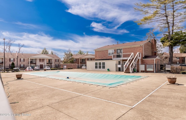 community pool featuring stairway, a patio, a residential view, and fence