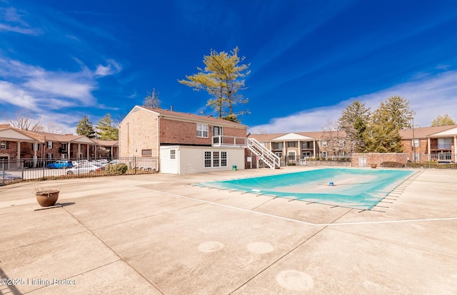 pool featuring stairs, a patio area, fence, and a residential view