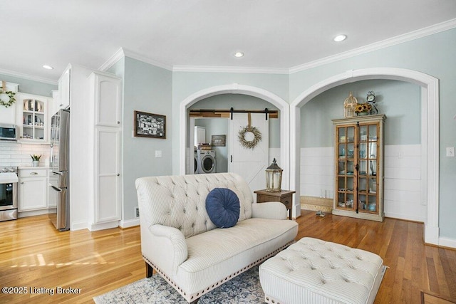 living room featuring light wood-style floors, arched walkways, separate washer and dryer, and a barn door