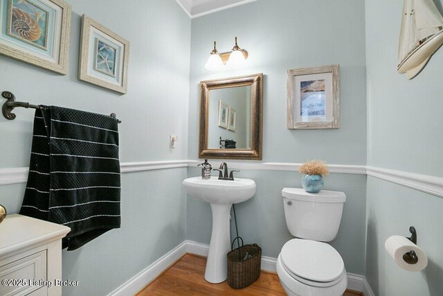 half bathroom featuring baseboards, toilet, and wood finished floors