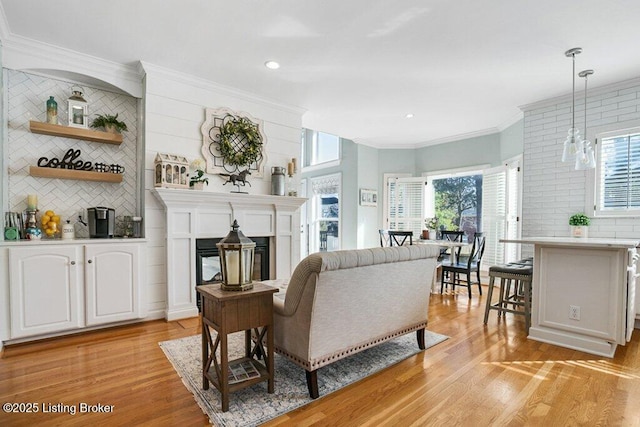 living room featuring a wealth of natural light, light wood-style flooring, and crown molding