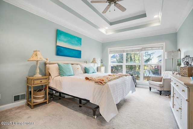 bedroom featuring visible vents, light colored carpet, a tray ceiling, and ornamental molding