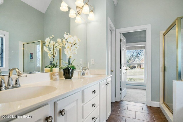 bathroom with stone tile floors, a shower stall, an inviting chandelier, and a sink