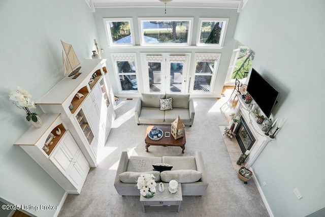 living area with a fireplace, a high ceiling, baseboards, and carpet floors