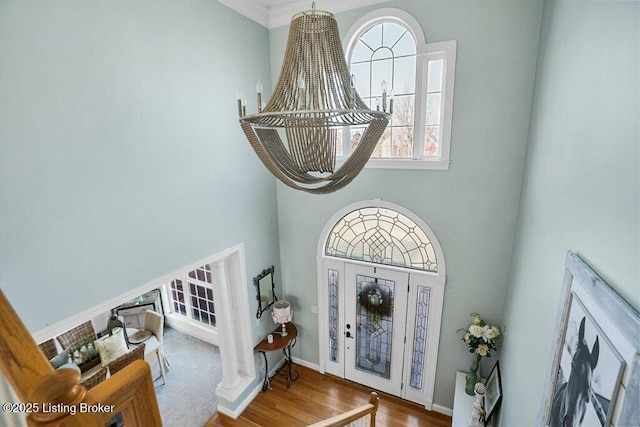 entrance foyer featuring a chandelier, baseboards, a high ceiling, and wood finished floors