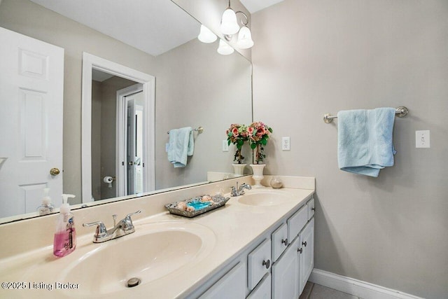 bathroom featuring double vanity, baseboards, and a sink