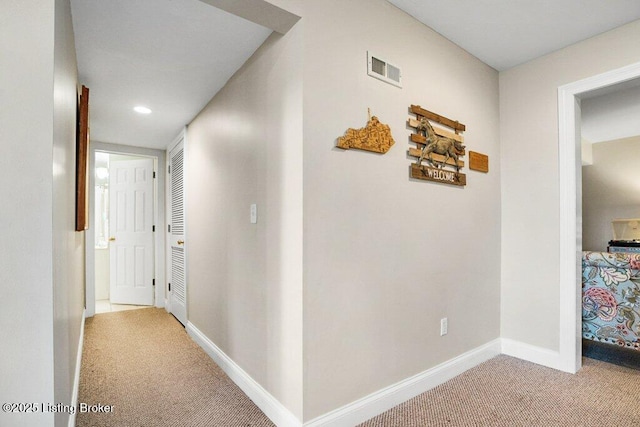 corridor featuring visible vents, baseboards, and carpet floors