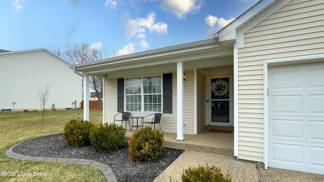 view of exterior entry featuring an attached garage, a lawn, and covered porch