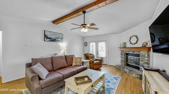 living room with lofted ceiling with beams, light wood-style floors, a stone fireplace, baseboards, and ceiling fan