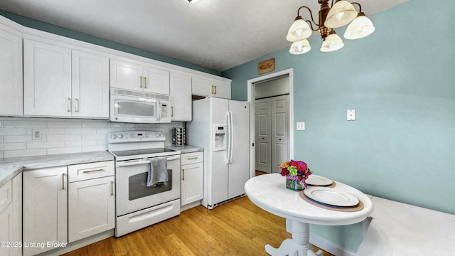 kitchen featuring light wood-style flooring, white appliances, white cabinets, light countertops, and decorative backsplash