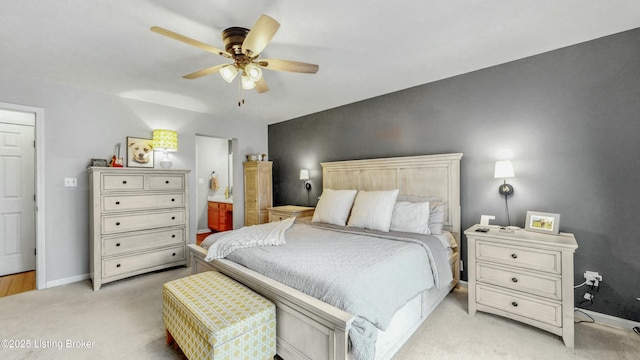 bedroom with light carpet, ceiling fan, ensuite bathroom, and baseboards