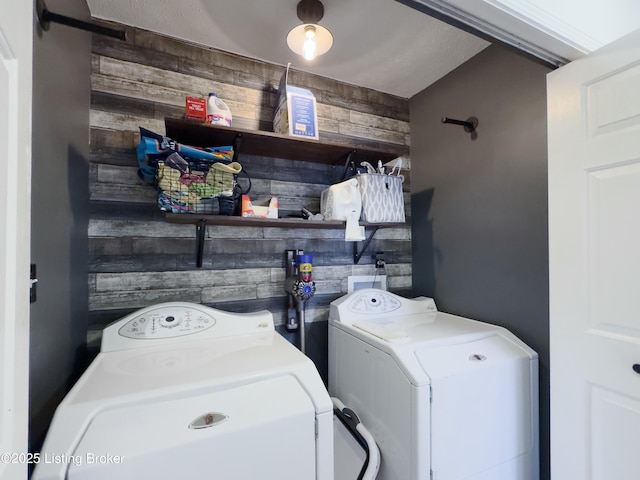 washroom featuring independent washer and dryer, wood walls, and laundry area