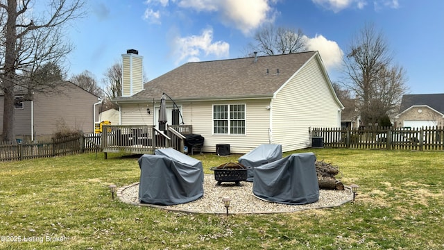 rear view of house with a deck, fence private yard, a lawn, and an outdoor fire pit