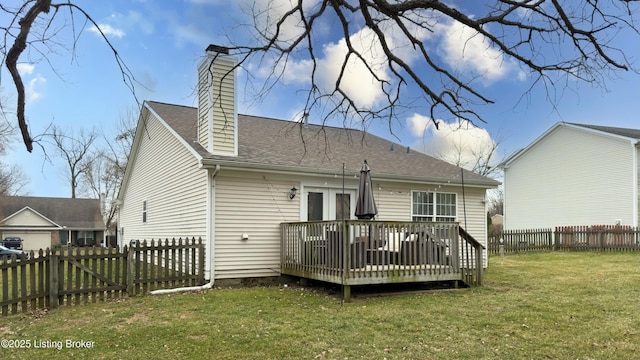 rear view of house featuring a lawn, a deck, a fenced backyard, a shingled roof, and a chimney