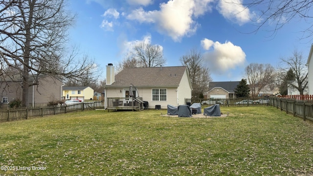 back of house with a yard, a deck, a fenced backyard, and a chimney