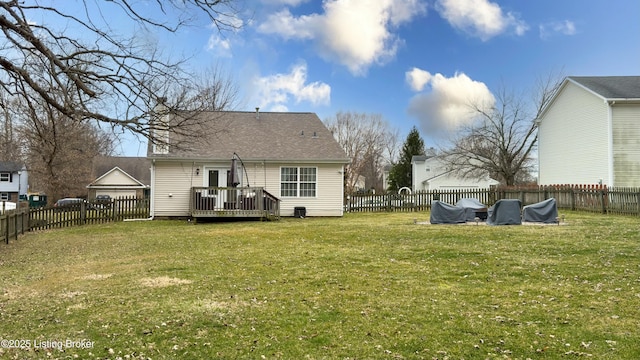 back of property with a wooden deck, a lawn, a fenced backyard, and a shingled roof