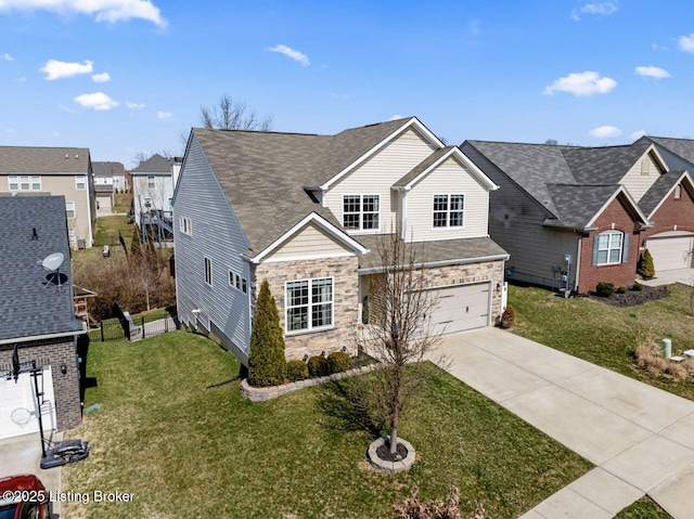 traditional home featuring a front lawn, stone siding, a residential view, concrete driveway, and a garage