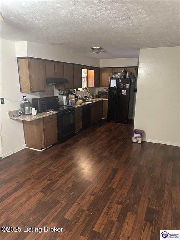 kitchen featuring dark brown cabinets, black appliances, dark wood-type flooring, under cabinet range hood, and a textured ceiling