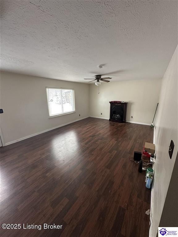 unfurnished living room with baseboards, dark wood-type flooring, ceiling fan, and a fireplace