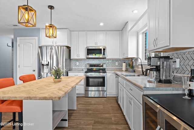 kitchen with visible vents, a breakfast bar, a sink, stainless steel appliances, and white cabinetry