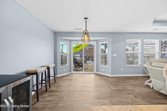 dining space featuring beverage cooler, visible vents, baseboards, and wood finished floors