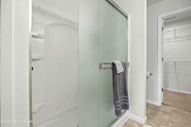 full bath with visible vents, a spacious closet, baseboards, and a stall shower